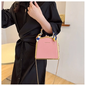 Detail of pink box bag with gold metal frame and silk scarf wrapped on the handle