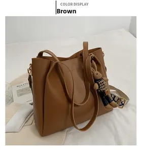 Brown large leather tote bag featuring an embroidered wide shoulder strap and rabbit charm