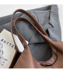 Detailed close-up of dark brown tote bag with litchi grain texture and magnetic closure