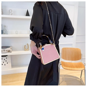 Pink structured box bag with gold metal trim and silk scarf wrapped on the handle