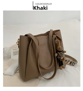 Detail of khaki leather tote bag with houndstooth bunny charm and printed wide shoulder strap