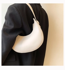 Minimalist white half-moon shoulder bag styled with a black blazer for a retro summer look