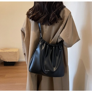 Detail of a large black soft leather shoulder bag with ruched design and white branding logo