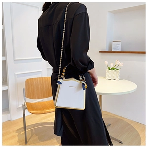 Detail of white leather box bag with gold metal frame and silk scarf handle accent