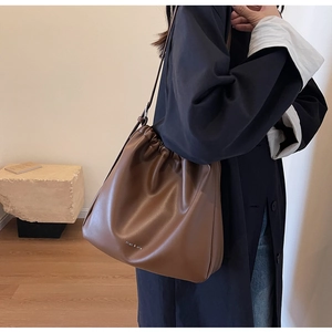 Detail of dark brown soft leather drawstring bucket bag with embossed logo lettering