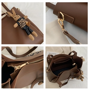 Detail view of brown leather tote bag with rabbit charm and gold hardware accents