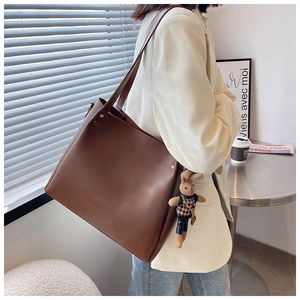 Close-up of a large dark brown tote bag with a cute plush rabbit charm on the strap