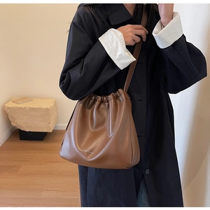 Close-up of brown soft leather bag with pleated cloud design and minimal logo detail