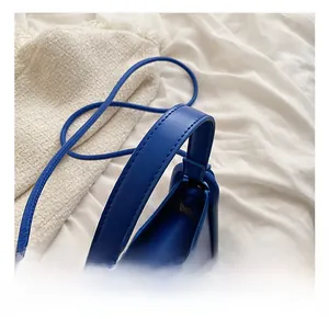 Macro detail of wide handle and stitching on matte Klein blue leather shoulder bag