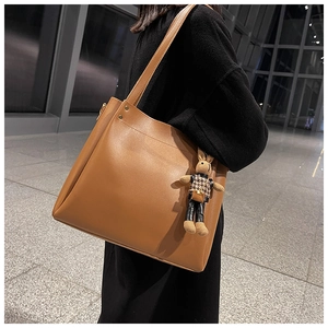 Detail of dark brown tote bag featuring a cute rabbit charm and sleek metal hardware
