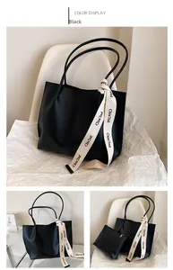 Detail of black faux leather tote bag with small pouch and chic lettered ribbon detail