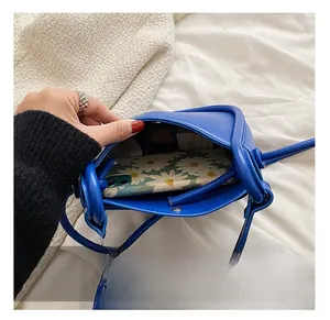 Detail view of Klein blue shoulder bag interior capacity showing phone and makeup