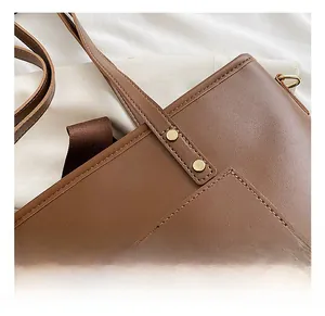 Close-up of brown matte leather tote with golden rivets and neat stitching details