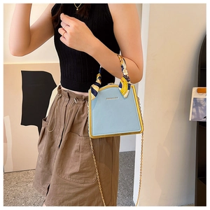Light blue faux leather handbag with gold frame and silk scarf detail on a model