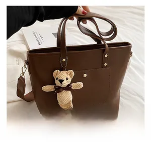 Close-up of dark brown leather tote bag with front pocket and cute teddy bear charm