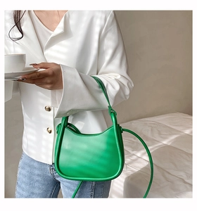 Detail of vibrant green crescent moon shoulder bag paired with an elegant white blazer