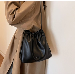 Detail of black drawstring bucket bag with miao & she logo on khaki trench coat