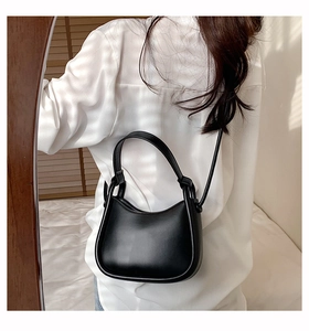 Detailed side view of a black crescent moon shoulder bag on a model in natural light