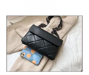 Close-up showing the size of black quilted chain bag compared to a phone case