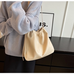 Detail of soft cream leather bucket bag with drawstrings and delicate brand lettering