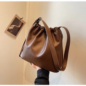 Detail of brown pleated leather shoulder bag with drawstring closure and silver hardware