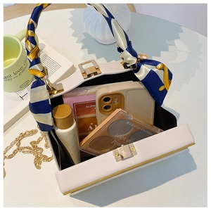 Dettaglio borsa a scatola bianca con manico in foulard di seta e tracolla dorata