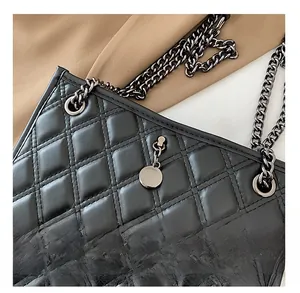 Detail of quilted leather texture and dark metallic chain strap on a black bag