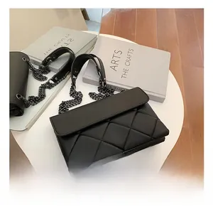 Detailed view of black quilted crossbody bag with metallic chain and sleek finish