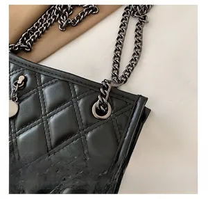 Detail of black quilted leather shoulder bag with gunmetal chain and stitching