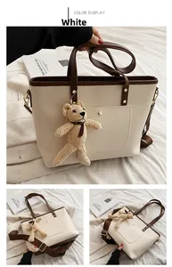 Detail view of white PU leather tote bag with brown handles and cute bear charm accessory
