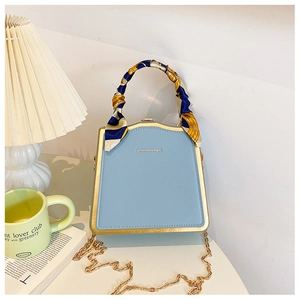 Dettaglio borsa a scatola azzurra con cornice dorata e manico avvolto in foulard di seta
