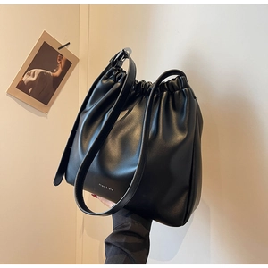 Detail of black soft leather bucket bag with pleated drawstring closure and white logo