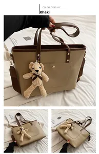 Detail view of khaki tote bag with dark brown straps and cute knitted bear charm