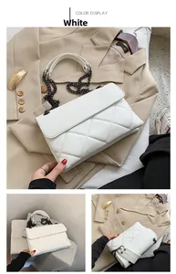 Detail of white quilted crossbody bag featuring metal chain strap and luxury texture