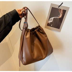 Detail of dark brown drawstring bucket bag with soft pebbled leather and brand logo