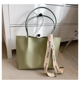 Detail view of large light green leather tote bag with printed webbing strap decoration