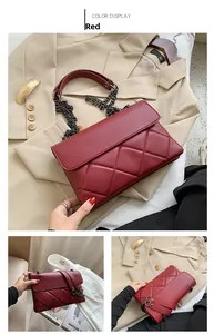 Detail of red quilted chain bag showing refined diamond patterns and black metal strap