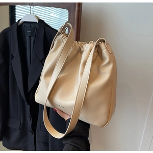 Detail of soft cream-colored tote bag featuring pleated top and adjustable wide strap
