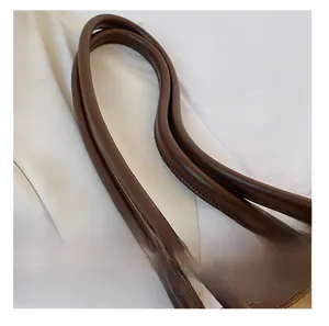 Close-up of brown leather shoulder strap with meticulous stitching on a white background