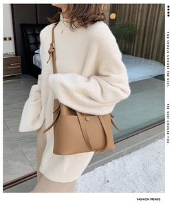 Close-up of brown faux leather bucket bag with adjustable straps and side knot detail