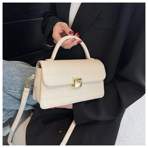 Detail of cream faux crocodile leather handbag with gold clasp and top handle