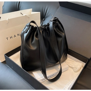 Detail of black pleated bucket bag with adjustable strap in luxury gift packaging