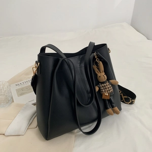 Black large capacity tote bag with rabbit charm and geometric print strap on white bedding