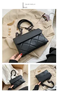 Detail view of black quilted faux leather crossbody bag with metallic chain and flap closure
