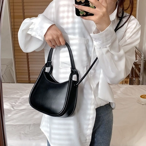 Minimalist black matte semi-circular crossbody bag with handle shown in a mirror selfie