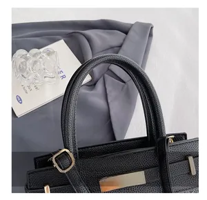 Detailed close-up of a black lychee texture leather handbag with a gold rotary lock