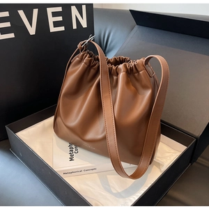 Detailed view of brown drawstring bucket bag featuring smooth leather texture and strap