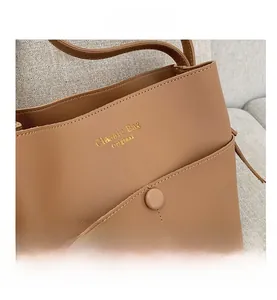 Detail of tan faux leather bucket bag featuring gold lettering and fine stitching texture