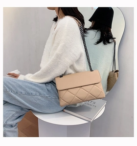 Quilted crossbody bag in beige leather with metal chain strap worn by a model