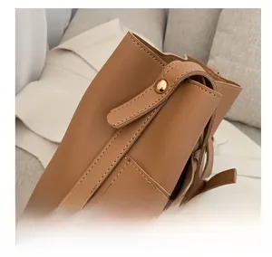 Close-up of brown bucket bag showing pebbled leather texture and metal magnetic closure